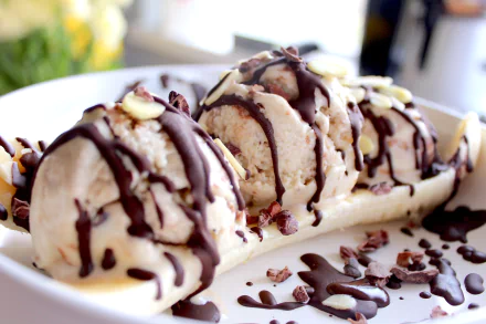HD desktop wallpaper featuring a close-up of a banana split topped with scoops of ice cream and drizzled with chocolate sauce.