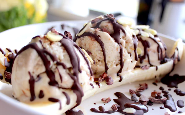 HD desktop wallpaper featuring a close-up of a banana split topped with scoops of ice cream and drizzled with chocolate sauce.