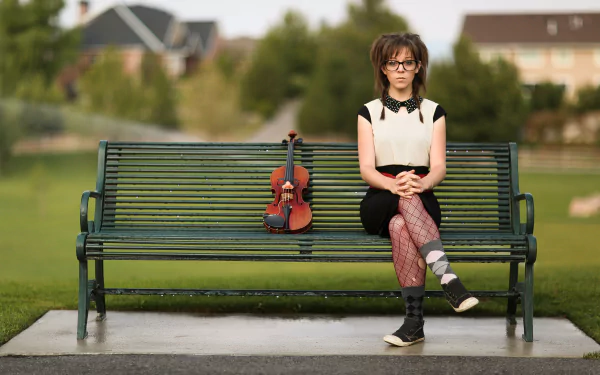 Lindsey Stirling sits on a park bench with a violin beside her, captured in a 4K Ultra HD music-themed PC desktop wallpaper.