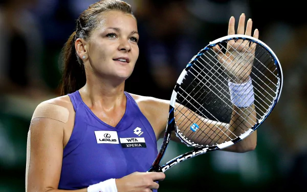 HD PC desktop wallpaper of a Polish tennis player in a purple top waving while holding a racket, sports action portrait captured mid-match.