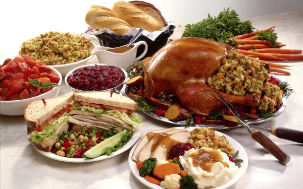HD PC desktop wallpaper featuring a classic Thanksgiving holiday feast with roasted turkey, stuffing, mashed potatoes, cranberry sauce, sandwiches, and fresh vegetables.
