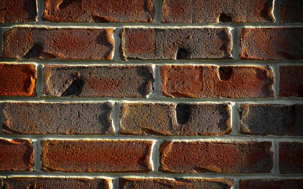 Close-up photography of weathered red brick wall with textured mortar and warm shadows — 4K Ultra HD PC desktop wallpaper background.