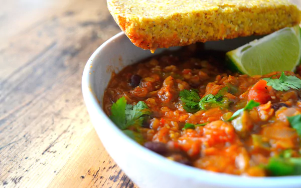 5K Ultra HD PC desktop wallpaper and background of food — a bowl of chunky chili garnished with cilantro and a lime wedge, crusty bread perched on the rim.