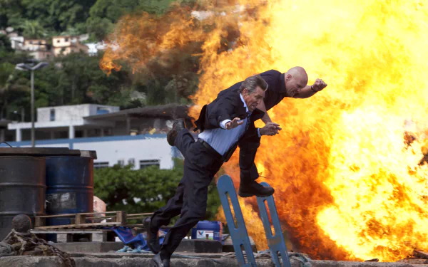 Action-packed scene from *The Expendables* featuring Monroe, Eric Roberts, Steve Austin, and Dan Paine, with a dramatic explosion in the background. 4K Ultra HD wallpaper.