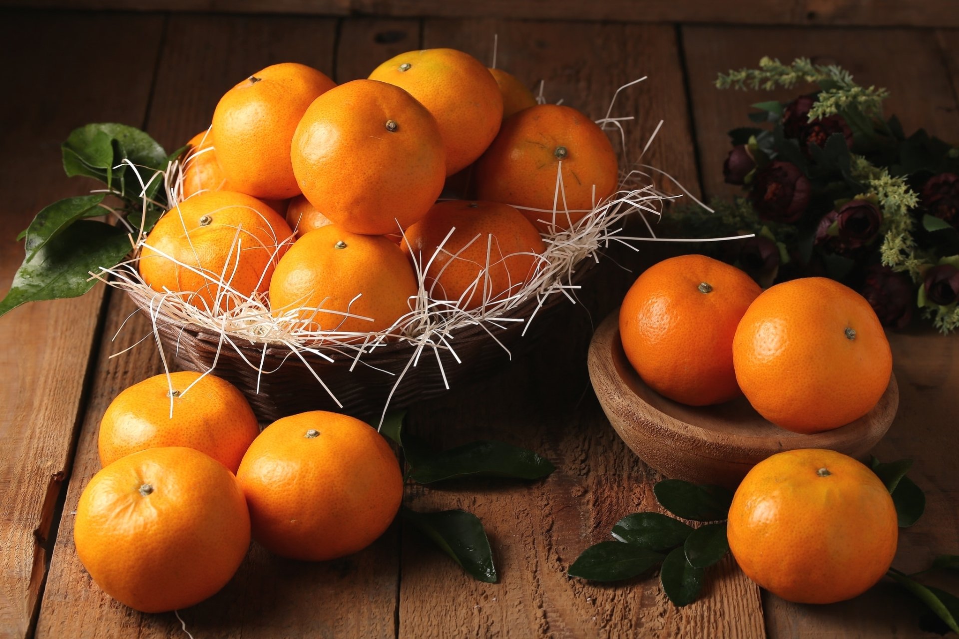 HD PC desktop wallpaper of mandarin fruit: basket and wooden bowls of bright mandarins on a rustic wooden table with scattered green leaves, a vivid food background.