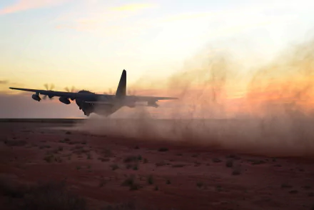 Military aircraft Lockheed MC-130 skims the desert at sunset, kicking up dust — HD PC desktop wallpaper and background.