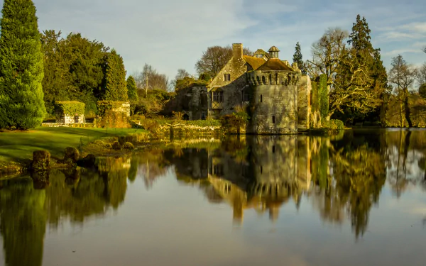 Reflection of the historic Scotney Castle and surrounding trees on a calm lake in England, captured in HD for a serene desktop wallpaper.