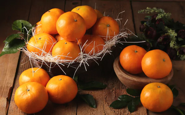 HD PC desktop wallpaper of mandarin fruit: basket and wooden bowls of bright mandarins on a rustic wooden table with scattered green leaves, a vivid food background.