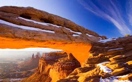 HD landscape of a glowing natural arch on a cliff at Arches National Park, Utah, USA, showcasing stunning rock formations under a vivid blue sky.