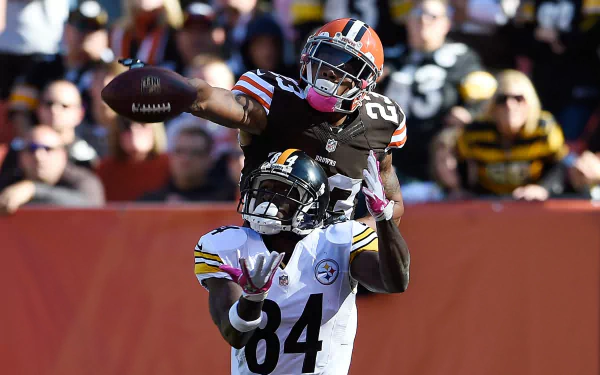HD PC desktop wallpaper and background: Cleveland Browns player leaping over an opponent for a contested catch, dynamic sports action.