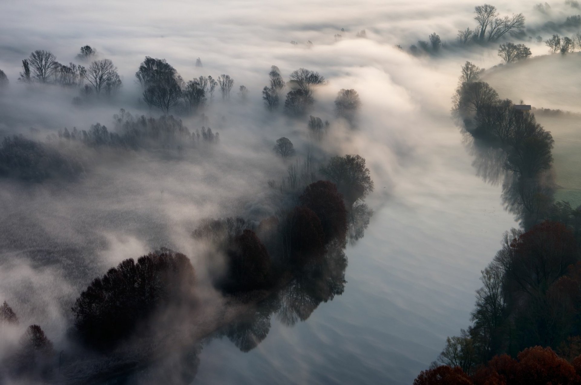 A serene landscape featuring a fog-covered river, surrounded by trees. This HD desktop wallpaper captures the tranquility of nature in a captivating scene.
