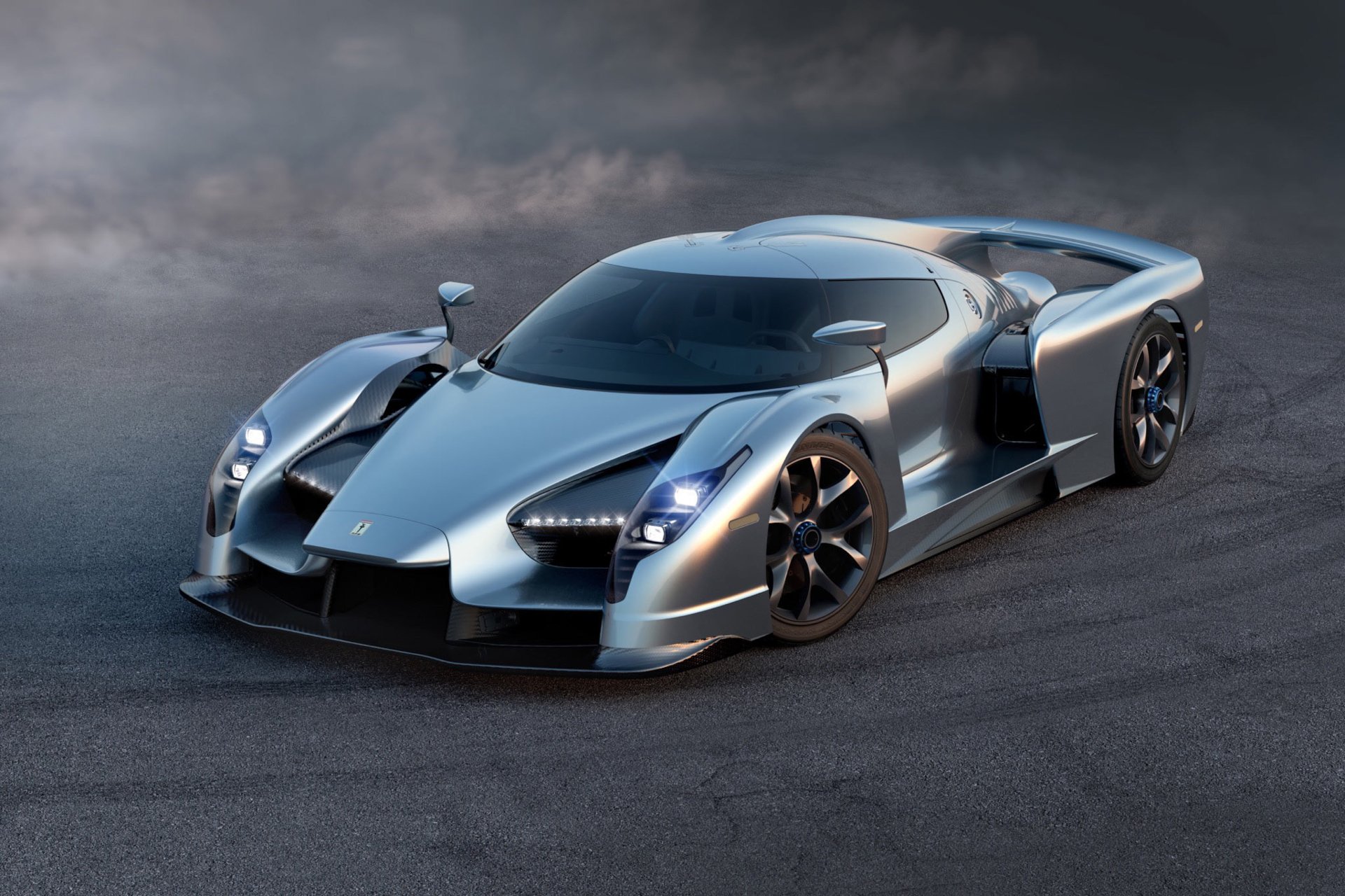 HD desktop wallpaper featuring a sleek silver SCG 003 Stradale supercar on a dark asphalt surface under a moody sky.