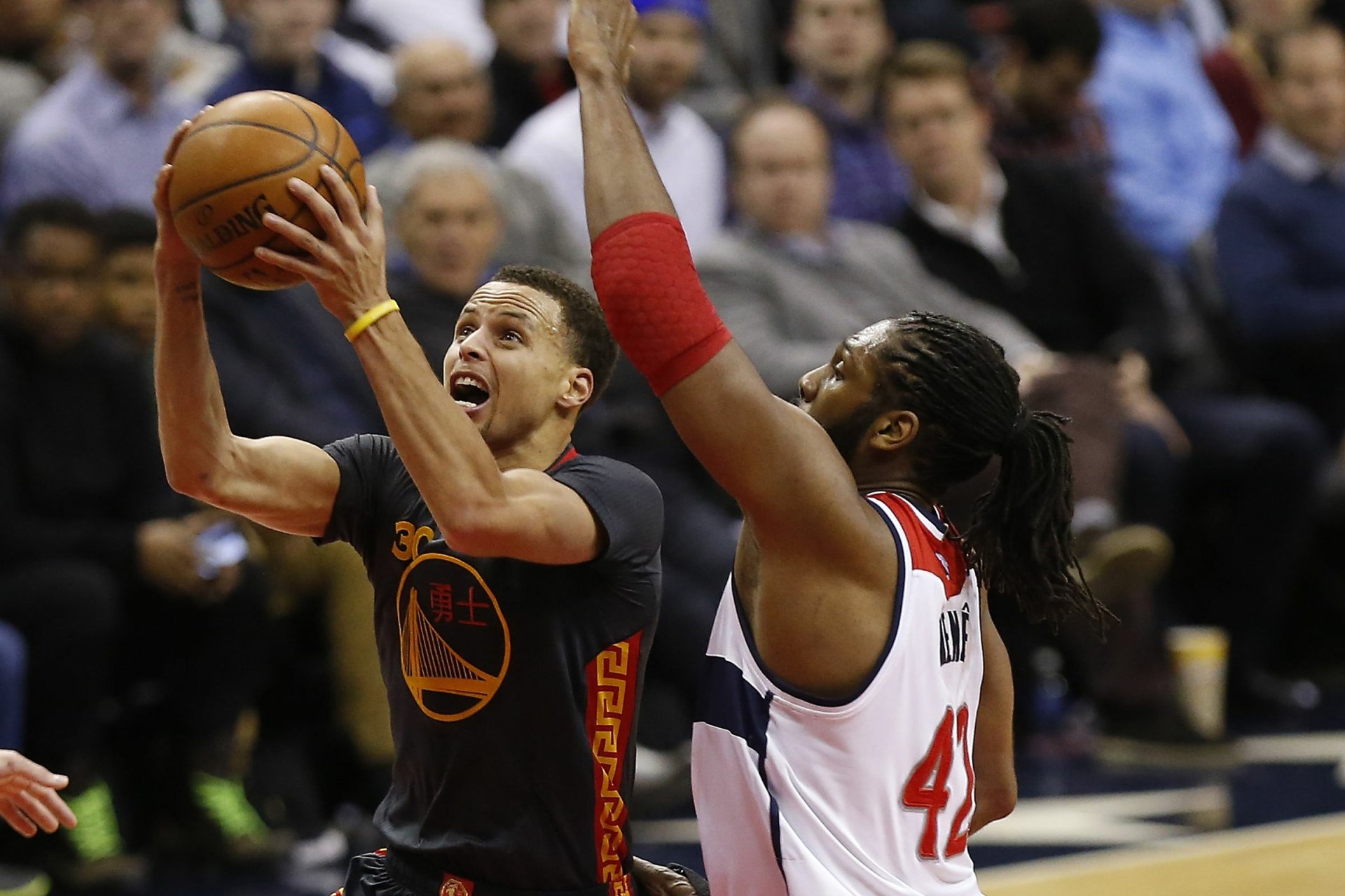 Stephen Curry of the Golden State Warriors takes a shot while being defended by an opponent in a high-energy basketball moment. HD wallpaper showcasing sports action.