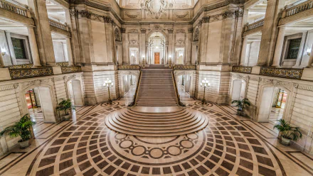 4K Ultra HD image of the grand interior architecture of San Francisco City Hall, showcasing its ornate stairway and detailed man-made design elements.