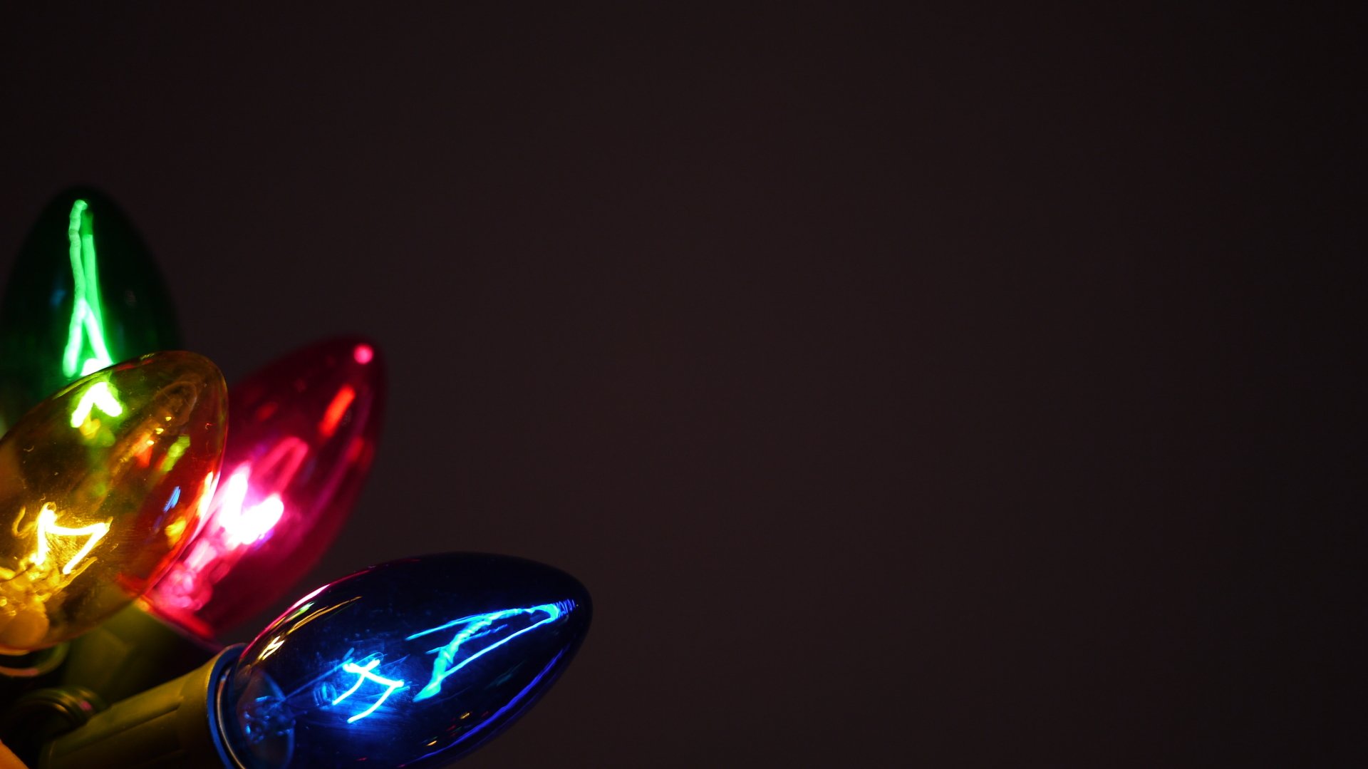 Close-up of colorful Christmas lights glowing against a dark background, captured in stunning 4K Ultra HD for a festive holiday PC desktop wallpaper.