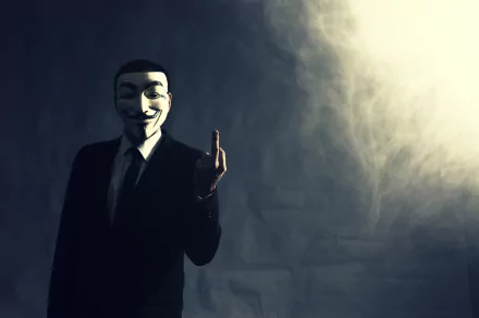 Dark-themed HD desktop wallpaper featuring a person in a suit wearing an Anonymous mask, set against a smoky, shadowy background representing technology and anonymity.