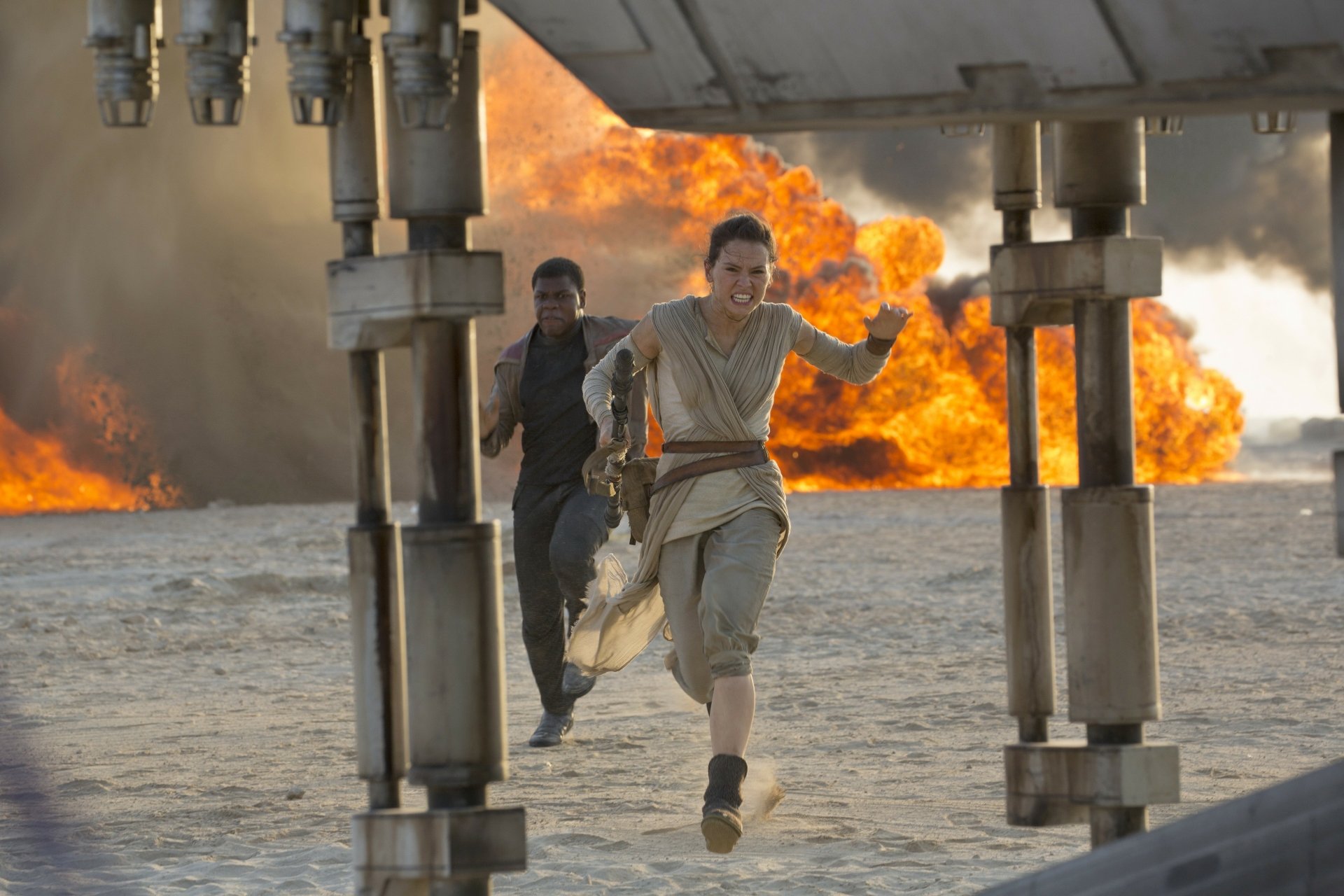 Rey and Finn sprint away from an explosion in this dynamic scene from Star Wars Episode VII: The Force Awakens, showcasing the thrill of adventure in the galaxy far, far away.