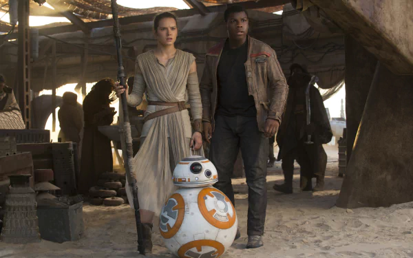 Rey and Finn stand together in a sandy setting, with BB-8 beside them, in a scene from Star Wars Episode VII: The Force Awakens. High-definition wallpaper capturing this dynamic trio.