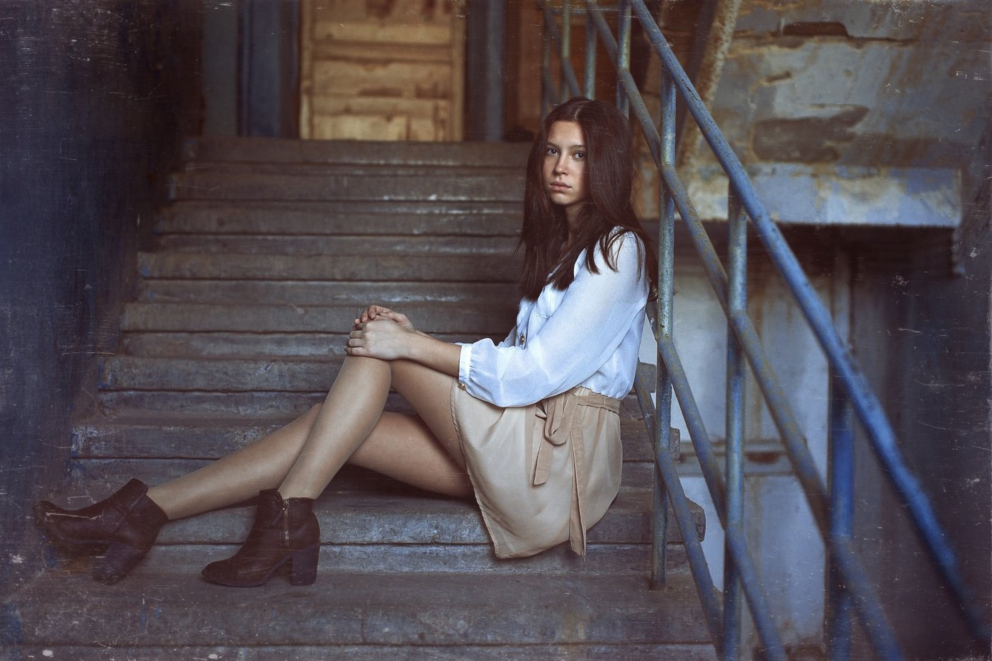 HD PC desktop wallpaper background showing a long-haired woman model sitting on worn concrete stairs in a light blouse and skirt, leaning against a metal railing.
