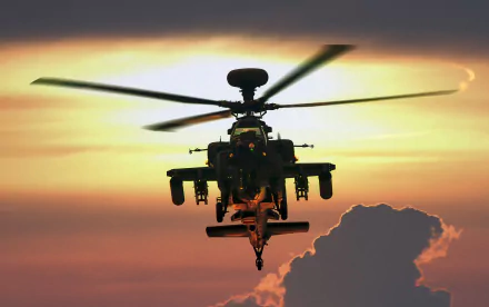 HD desktop wallpaper of a military Boeing AH-64 Apache helicopter silhouetted against a vibrant sunset sky.