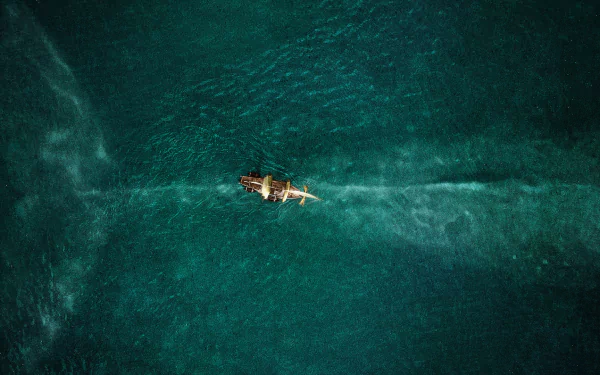 Aerial view of a lone ship cutting a trail through deep teal ocean, from the movie In the Heart of the Sea — HD PC desktop wallpaper and background.