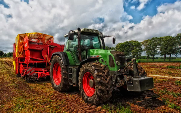A vibrant HDR image of a Fendt tractor working in a farm field, paired with a bright red agricultural vehicle, under a cloudy blue sky, creating a striking HD desktop wallpaper.