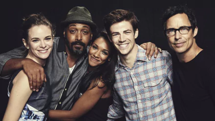 A HD desktop wallpaper featuring actors from the TV show The Flash (2014): Danielle Panabaker, Jesse L. Martin, Candice Patton, Grant Gustin, and Tom Cavanagh, smiling and posing together.