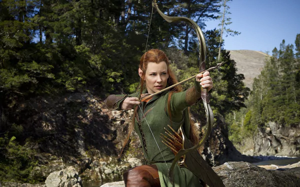 Elven archer from The Hobbit: The Desolation of Smaug draws her bow on a rocky riverside; HD PC desktop wallpaper/background.