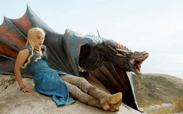 HD wallpaper featuring Emilia Clarke as Daenerys Targaryen from Game of Thrones, sitting beside a dragon against a scenic backdrop.
