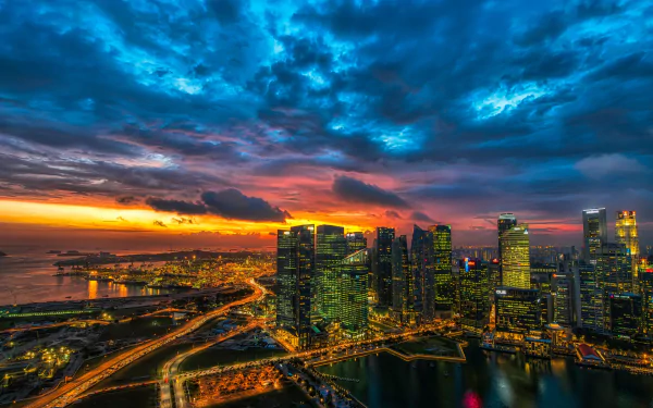 A stunning sunset over Singapore's cityscape, showcasing vibrant clouds and city lights reflecting on the water, captured in 4K Ultra HD detail.