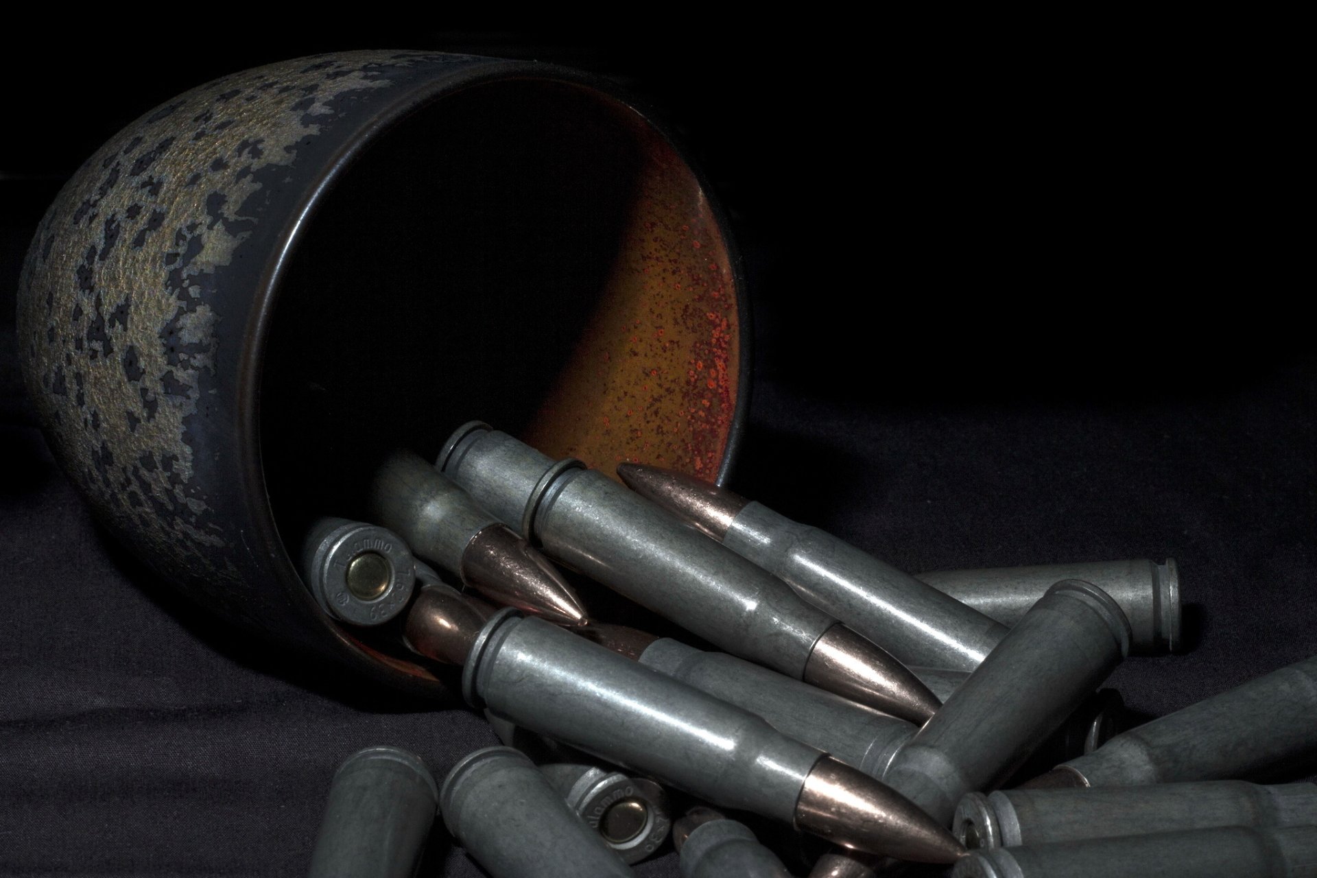 HD PC desktop wallpaper featuring a close-up of man-made bullets spilling from a rusted container against a dark background.