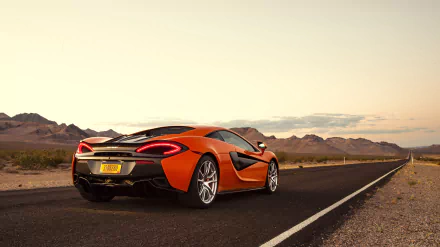 Orange McLaren 570S supercar parked on a desert road at sunset, captured in 4K Ultra HD for a striking PC desktop wallpaper and background.