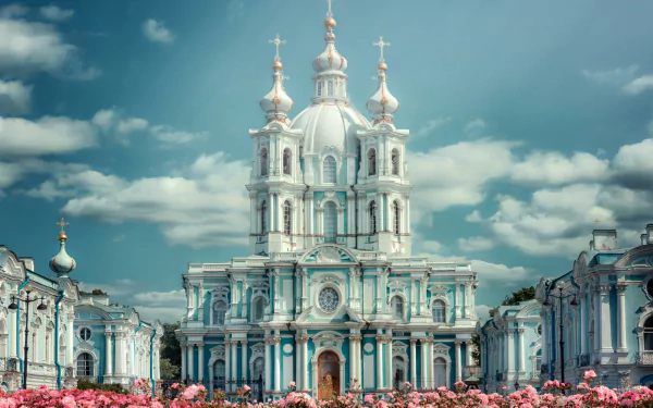 Smolny Cathedral at Smolny Convent in Russia: blue-and-white baroque domed cathedral framed by pink flowers under a cloudy sky, HD desktop wallpaper.