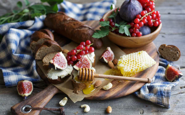 HD PC desktop wallpaper still life: figs, red currants, sliced bread, honeycomb with dipper on a wooden board, nuts and blue check cloth.