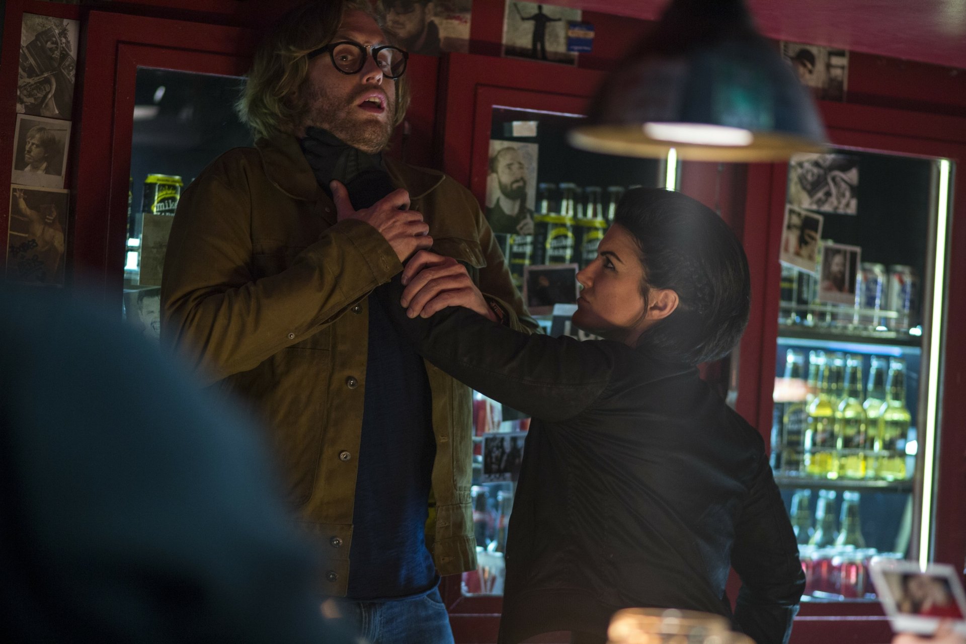 A dramatic scene from the movie Deadpool, featuring Angel Dust and Gina Carano in an intense moment, set against a vibrant bar backdrop. HD wallpaper showcasing cinematic action.
