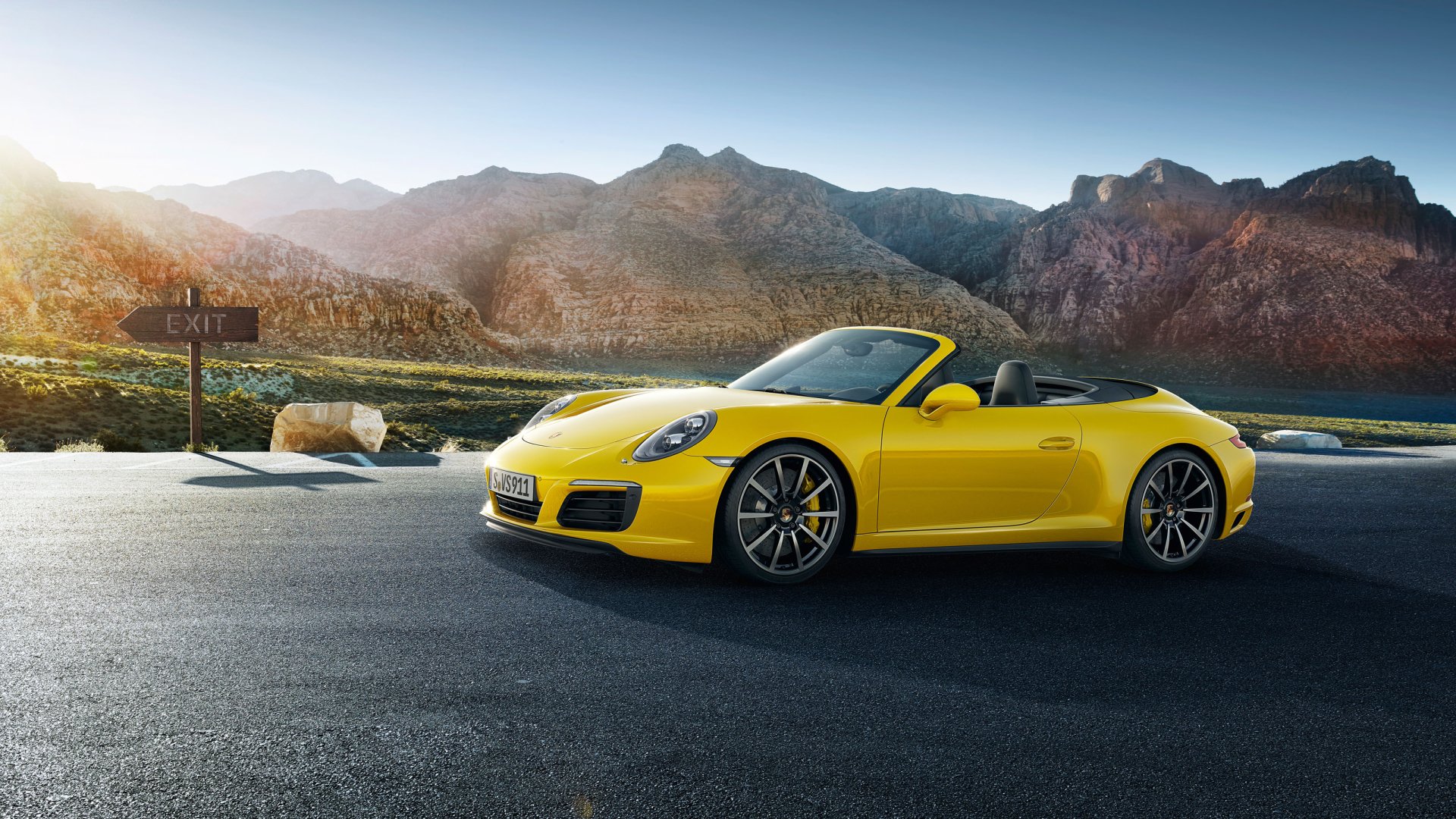 Yellow Porsche 911 Carrera 4S convertible on a mountain road at sunrise, high-detail 2K Quad HD PC desktop wallpaper of a Porsche 911 Carrera sports car.