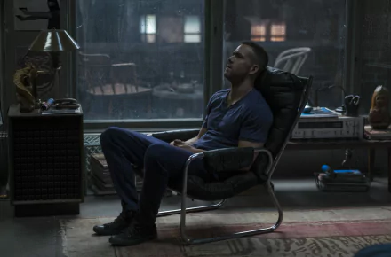 Ryan Reynolds as Deadpool sits introspectively in a chair, surrounded by a dimly lit room, captured in this HD wallpaper that highlights the film’s moody atmosphere.