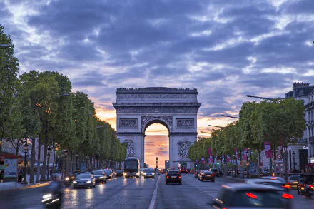 A stunning view of the Arc de Triomphe in Paris, framed by tree-lined streets and a colorful sunset, captured in high-definition for a vibrant desktop wallpaper.