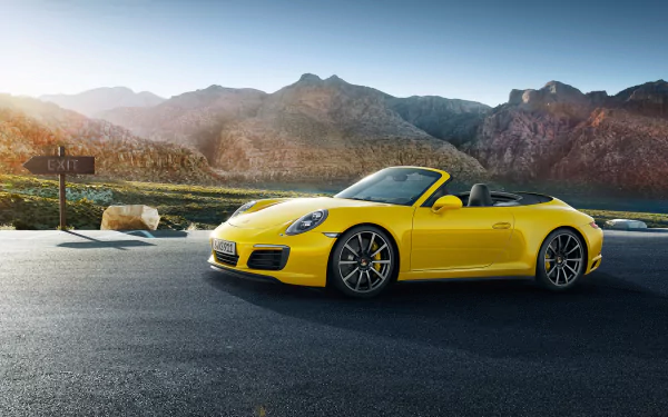 Yellow Porsche 911 Carrera 4S convertible on a mountain road at sunrise, high-detail 2K Quad HD PC desktop wallpaper of a Porsche 911 Carrera sports car.