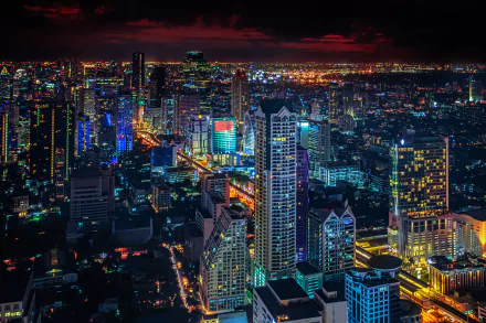 A vibrant night cityscape of Bangkok, Thailand, showcasing illuminated skyscrapers and sprawling urban lights in this HD PC desktop wallpaper.