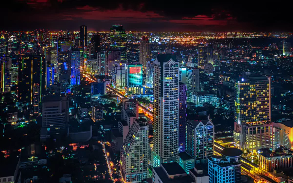 A vibrant night cityscape of Bangkok, Thailand, showcasing illuminated skyscrapers and sprawling urban lights in this HD PC desktop wallpaper.