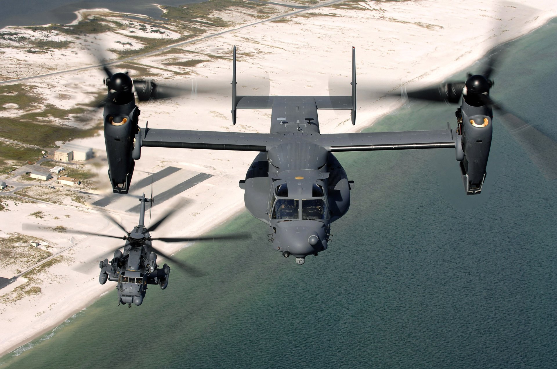 HD desktop wallpaper featuring a Sikorsky MH-53 helicopter flying alongside a Bell Boeing V-22 Osprey over a coastal landscape.