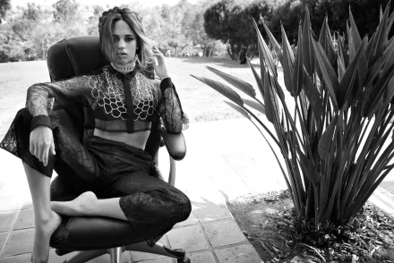 Black and white HD desktop wallpaper featuring Swedish actress and celebrity Alicia Vikander seated outdoors in a stylish outfit.