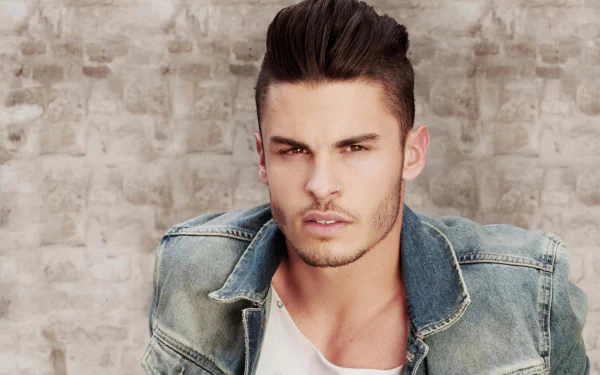 2K PC desktop wallpaper: close portrait of a French male model in a denim jacket against a textured grey background.