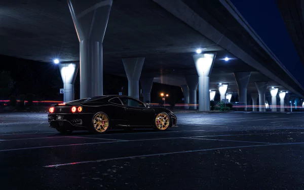 A sleek black Ferrari 360 Modena supercar parked under illuminated highway overpasses at night in this HD desktop wallpaper.