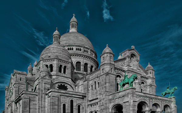 4K Ultra HD image of the Sacré-Cœur Basilica in Paris, France, showcasing its iconic domes, religious statues, and detailed architectural monument against a deep blue sky.