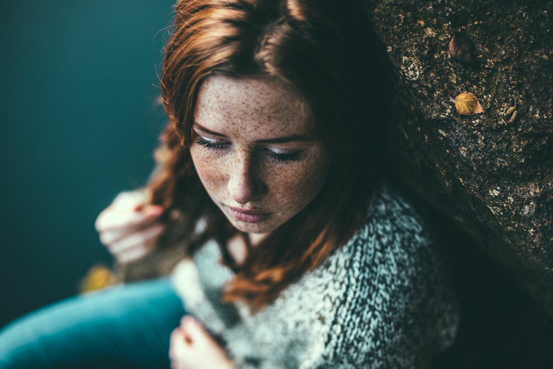 HD PC desktop wallpaper: moody portrait of a redhead woman with freckles, braided hair, blurred bokeh background, thoughtful expression.