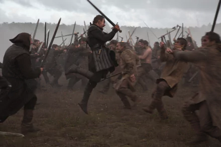 Epic battlefield shot from the movie Macbeth: lead actor mid-jump with sword amid clashing soldiers — 5K Ultra HD PC desktop wallpaper.