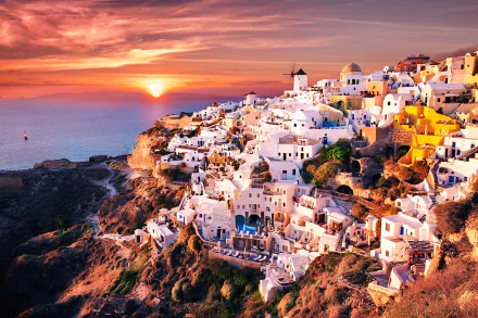 A stunning sunset over the iconic architecture of Santorini, Greece, showcasing whitewashed buildings perched on cliffs, with the Aegean Sea in the background.