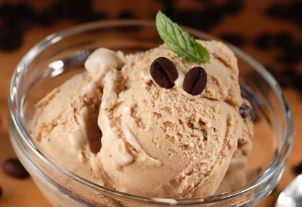Close-up of creamy coffee ice cream in a glass bowl, garnished with fresh mint leaves and coffee beans, presented as an HD desktop wallpaper background.